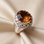 Top view of the faceted oval citrine showing the facets and the beaded silver rim of the setting
